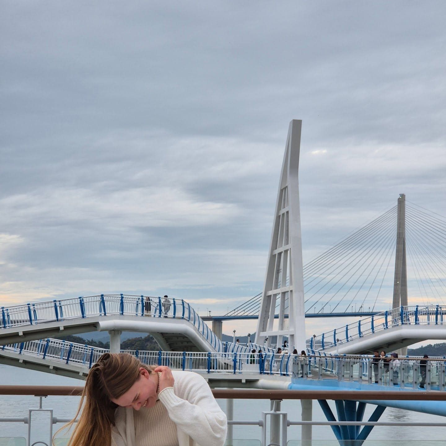 A traveller laughing on the skywalk with a cable-stayed bridge behind